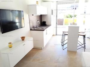 eine Küche mit weißen Schränken und einem TV an der Wand in der Unterkunft Résidence Héliopolis Bâtiment D - Appartements pour 2 Personnes 584 - Naturiste in Cap d'Agde