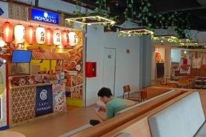 a man sitting in a restaurant looking at a cell phone at Student Haven Compact Studio at B Residence BSD in Cilandak