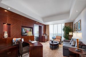 Habitación de hotel con escritorio y sofá en Songjiang New Century Grand Hotel Shanghai, en Songjiang