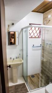 een badkamer met een glazen douche en een wastafel bij Quatro Estações Hospeda L 11 - Conforto para família no Capivari in Campos do Jordão