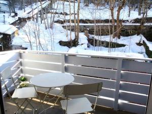 una mesa y 2 sillas en un balcón con nieve en Résidence Oustal - 3 Pièces pour 8 Personnes 354 en Barèges