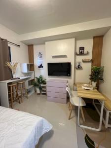 a bedroom with a bed and a desk and a television at Kristinas Homestay- Cozy Resort Vibe Condotel in Cebu City