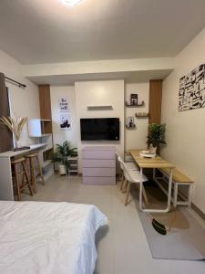 a bedroom with a bed and a desk and a television at Kristinas Homestay- Cozy Resort Vibe Condotel in Cebu City