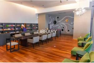 Regalia Exclusive Hostel في كوالالمبور: مكتبة فيها كراسي وطاولة في الغرفة