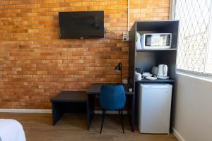 a room with a desk and a tv on a brick wall at The Club Hotel in Gladstone