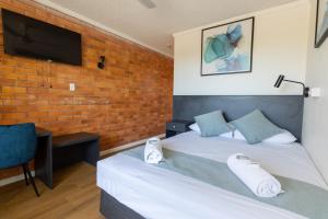 Schlafzimmer mit einem Bett, einem Schreibtisch und einem TV in der Unterkunft The Club Hotel in Gladstone