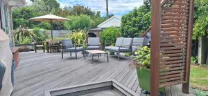 una terraza con sillas, mesas y sombrilla en Reeves Retreat-Handy in Tasman, en Nelson