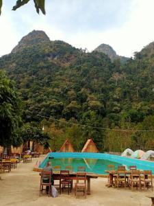 a man sitting at tables in front of a swimming pool at NongKhiaw CampingSite Swimming Pool in Ban Nongkham