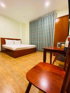 Schlafzimmer mit einem Bett, einem Tisch und einem Schreibtisch in der Unterkunft Dũng India Hotel in Ho-Chi-Minh-Stadt