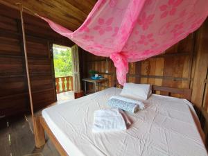 a bedroom with a bed with a pink mosquito net at Banlung Mountain View Treks & Tours in Banlung