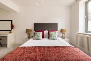 1 dormitorio con 1 cama blanca grande con almohadas rojas en Wild Roses Serviced Apartments - Borough, en Londres