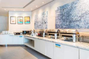 a restaurant kitchen with white cabinets and stainless steel counters at Jinjiang Inn Shanghai Light Textile Market Caoan Road in Shanghai