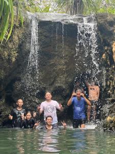 a group of people standing in the water near a waterfall at Daya Farm and Adventure 