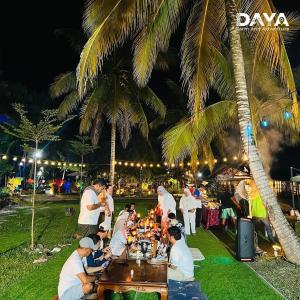 een groep mensen die rond een tafel zitten met eten bij Daya Farm and Adventure 