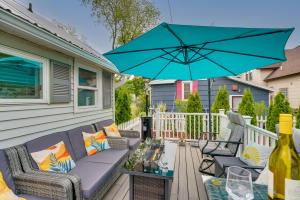 een patio met een bank en een tafel met een blauwe parasol bij Dog-Friendly Manistee Home with Deck, 2 Mi to Beach! in Manistee