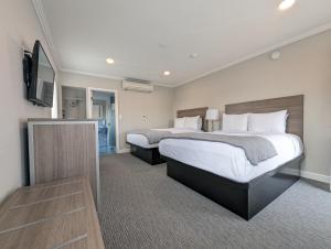 Habitación de hotel con 2 camas y TV de pantalla plana. en Ocean Park Inn en Los Ángeles