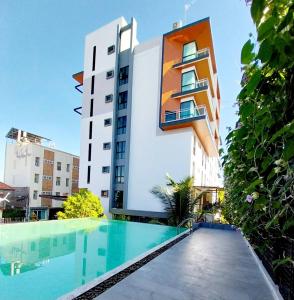 a building with a swimming pool in front of a building at The Vita Plus Hotel in Ban Kohong