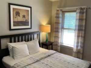 um quarto com uma cama com almofadas brancas e uma janela em The House Hotels- Thoreau Upper - Lakewood - 10 Minutes to Downtown Attractions em Lakewood