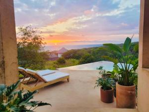 a patio with a couch and a sunset in the background at Casa Naya in Puerto Escondido