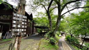 Yumoto的住宿－Tabino Camping Base Akiu Tree House - Vacation STAY 23967v，树木丛生的建筑物前的街道标志