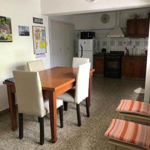 eine Küche mit einem Holztisch und weißen Stühlen in der Unterkunft AlquilertemporarioGP in General Pico