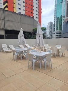 een groep tafels en stoelen met witte parasols bij Apartamento na Quadra do Mar com pisicina in Balneário Camboriú