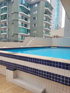 een zwembad met blauwe en witte tegels op een gebouw bij Apartamento na Quadra do Mar com pisicina in Balneário Camboriú