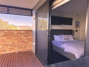 ein Schlafzimmer mit einem Bett und einem Balkon in der Unterkunft Hobart Haven Scenic 4BR with Mountain & Water Views in Sorell
