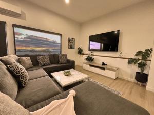 ein Wohnzimmer mit einem Sofa und einem Flachbild-TV in der Unterkunft Hobart Haven Scenic 4BR with Mountain & Water Views in Sorell