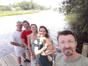 eine Gruppe von Menschen, die mit einem Hund auf einem Dock stehen in der Unterkunft Sítio com piscina Hidromassagem com acesso ao Rio Mampituba in Passo de Torres