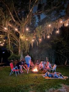 un grupo de personas sentadas alrededor de un fuego por la noche en Sítio com piscina Hidromassagem com acesso ao Rio Mampituba en Passo de Torres