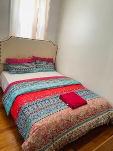 a bed with a red blanket and pillows on it at Muna’s Place in Newark