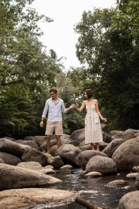 a man and a woman standing on rocks in the water at Kusfarm Bali in Selemadeg