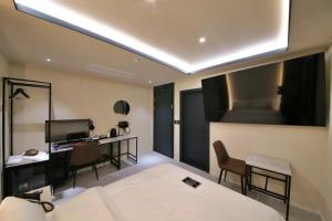 大田的住宿－Hotel141，一间卧室配有一张床、一张书桌和一台电视