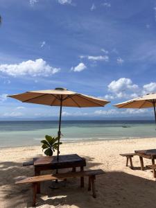 two picnic tables and an umbrella on a beach at Marika Resort in Badian