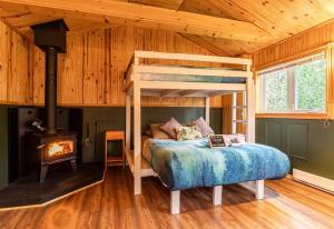 a bedroom with a bunk bed and a wood stove at Refuge Rustic bordé par rivière et la nature in Sainte-Germaine-du-Lac-Etchemin