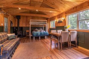 a living room with a table and a bed at Refuge Rustic bordé par rivière et la nature in Sainte-Germaine-du-Lac-Etchemin