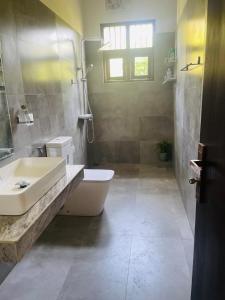 a bathroom with a sink and a tub and a toilet at Guruge Home Stay in Ambalantota