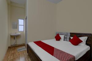 a bedroom with a bed with red pillows and a sink at OYO Flagship Prachi Guest House in Gorakhpur