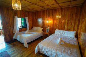 a bedroom with two beds in a wooden room at Marika Resort in Badian