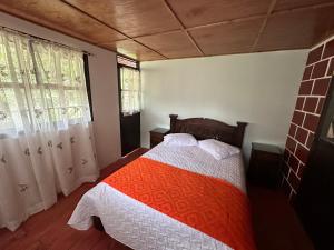 um quarto com uma cama com um cobertor vermelho e branco em sol solegüa em Cajamarca