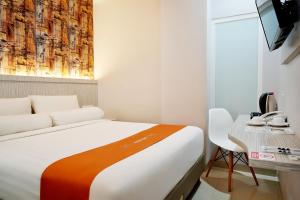 a bedroom with a bed and a table and a television at Front One Hotel Sragen in Sragen