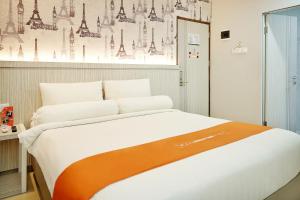 a bedroom with a large bed with an orange and white blanket at Front One Hotel Sragen in Sragen