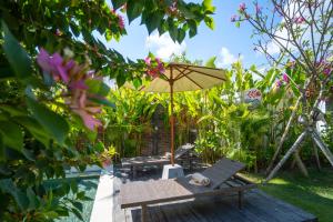 eine Terrasse mit einer Bank und einem Sonnenschirm in der Unterkunft Vicolo ArtVillas in Uluwatu