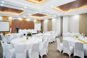 un salón de banquetes con mesas blancas y sillas blancas en Front One Hotel Sragen, en Sragen