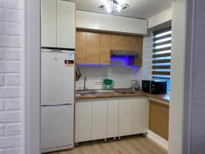 una cucina con mobili bianchi e un frigorifero bianco di 1-комнатная квартира a Ekibastuz