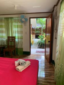 a room with a red bed with a towel on it at Divinagracia Cottages in San Vicente