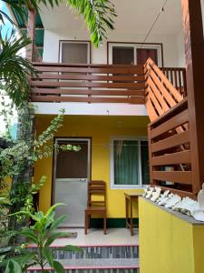 une maison avec un mur jaune et une terrasse en bois dans l'établissement Divinagracia Cottages, à San Vicente