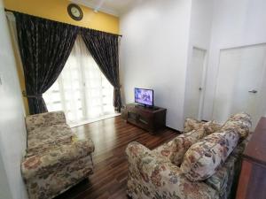 a living room with a couch and a tv at Awang's Villa Homestay in Kampong Gong Badak