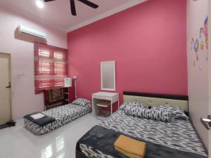 a bedroom with two beds and a pink wall at Awang's Villa Homestay in Kampong Gong Badak